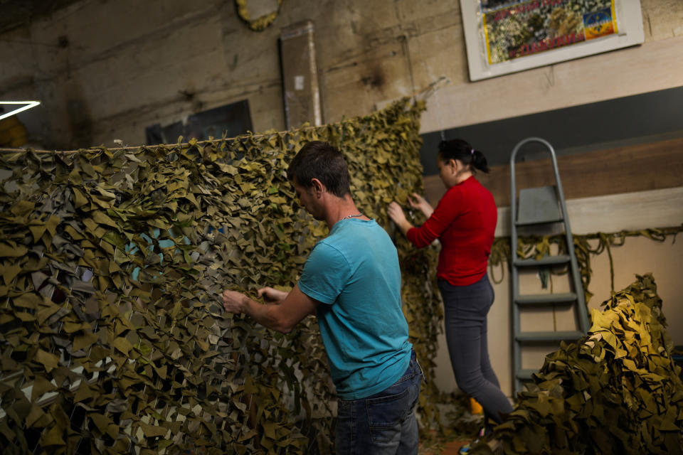 Volunteer make a camouflage net at a facility producing material for Ukrainian soldiers in Zaporizhzhia, Ukraine, Friday, May 6, 2022. An old industrial complex in the southeastern Ukrainian riverside city of Zaporizhzhia has become a hive of activity for volunteers producing everything from body armor to camouflage nets, anti-tank obstacles to heating stoves and rifle slings for Ukrainian soldiers fighting the Russian invasion. (AP Photo/Francisco Seco)