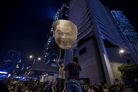 Protesters carry a defaced cutout of Hong Kong Chief Executive Leung Chun-ying, as they protest near the central government offices in the business district of Admiralty in Hong Kong in this September 29,2014 file photo. REUTERS/Tyrone Siu/Files