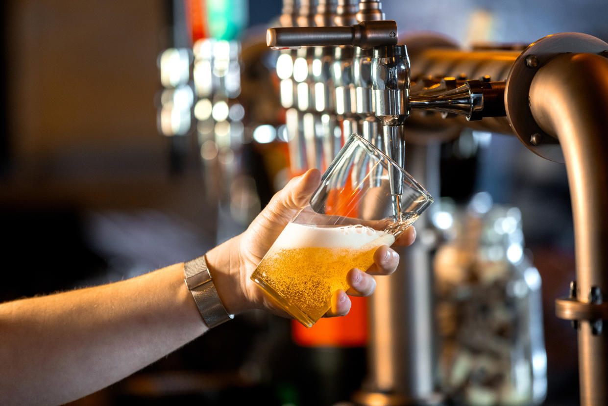 A close-up of an unrecognisable person's hand holding a pint glass at an angle being filled with lager. The lager is golden in colour creating foam and bubbles.

Videos are available similar to this scenario