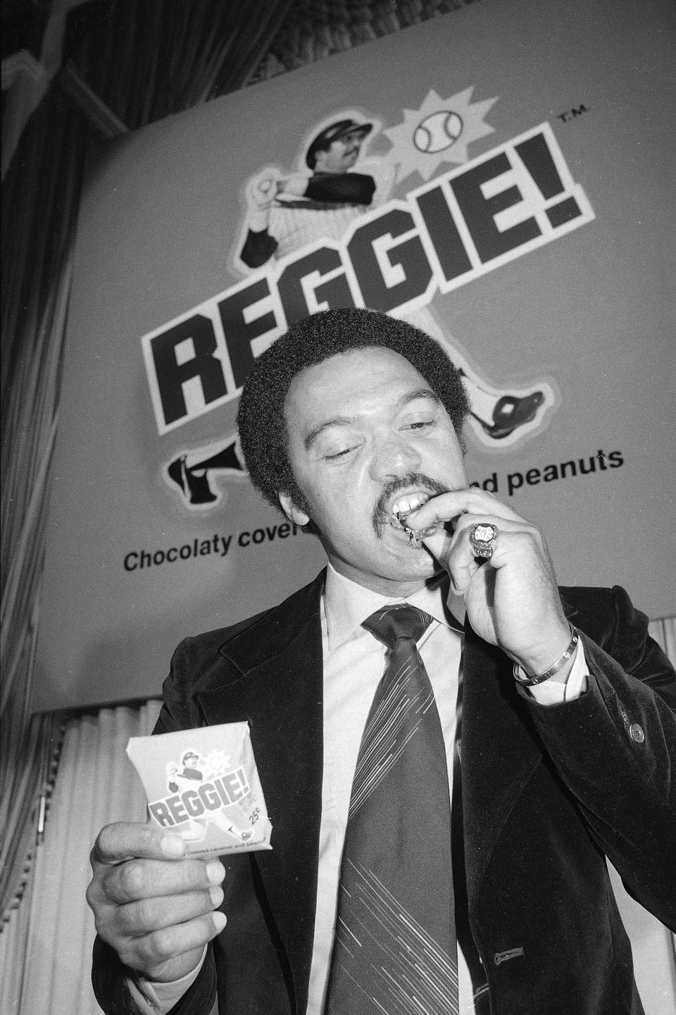 FILE - New York Yankees slugger Reggie Jackson, wearing a ring commemorating the Yankees' 1977 World Series victory, samples a new Reggie! candy bar in New York, in this Feb. 22, 1978, file photo. (AP Photo/Dave Pickoff, File)