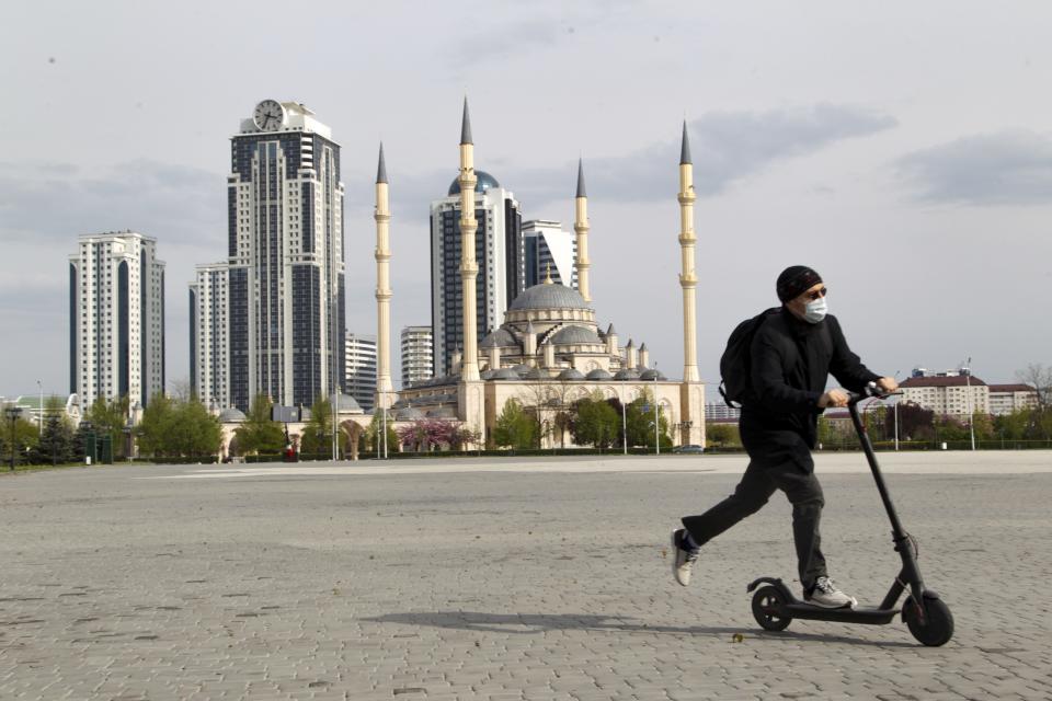 A man rides a scooter through an empty square in front of closed the Central Mosque "Heart of Chechnya" in Grozny, Russia, Thursday, April 23, 2020. Ramadan begins with the new moon later this week as Muslims all around the world are trying to work out how to maintain the many cherished rituals of Islam's holiest month amid the virus pandemic. (AP Photo/Musa Sadulayev)