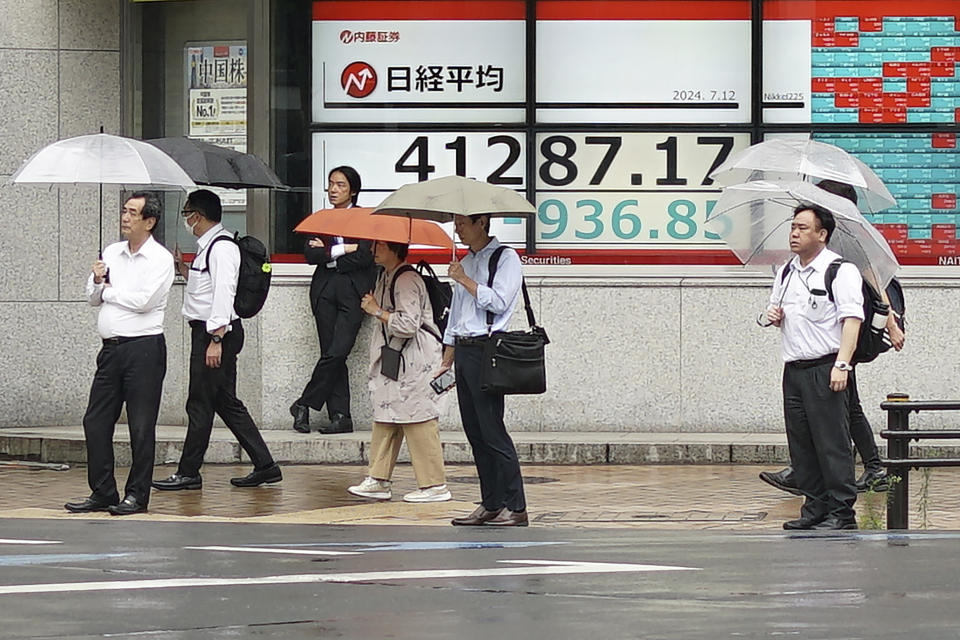 People walk in front of an electronic stock board showing Japan's Nikkei index at a securities firm Friday, July 12, 2024, in Tokyo. (AP Photo/Eugene Hoshiko)