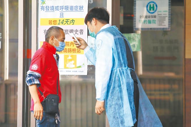 為防堵疫情，衛福部台北醫院保全穿著防護服，為進入的民眾量測體溫。（杜宜諳攝）