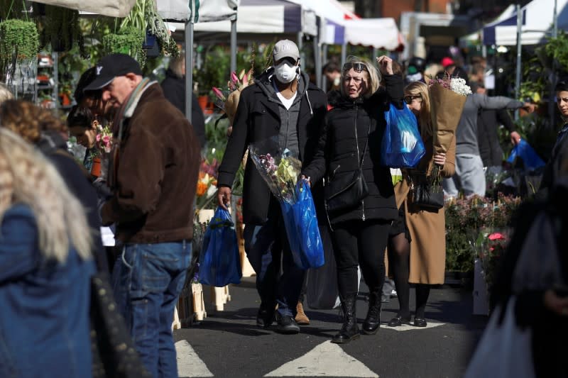 A man wearing a protective face mask walks through Columbia Road Flower Market, during the coronavirus disease (COVID-19) outbreak, on Mother's Day in London