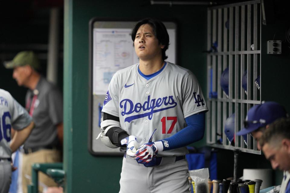 Shohei Ohtani of the Dodgers stands in the dugout after grounding out during the fourth inning against the Cincinnati Reds.