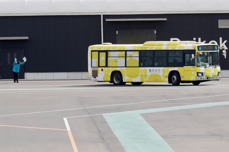 A man waves as a bus believed to be carrying some passengers from the cruise ship Diamond Princess, leaves at Daikoku Pier Cruise Terminal in Yokohama, south of Tokyo