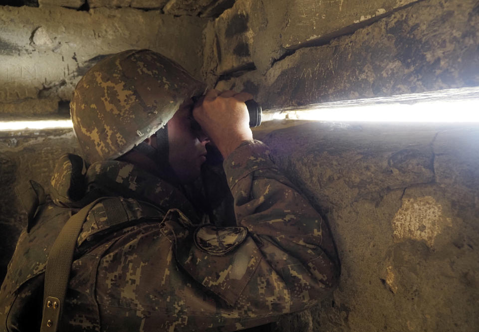 An Ethnic Armenian soldier looks through a binoculars toward Azerbaijan's positions from a dugout at a fighting position on the front line, during a military conflict against Azerbaijan's armed forces in the separatist region of Nagorno-Karabakh, Wednesday, Oct. 21, 2020. Armenia's prime minister has urged citizens to sign up as military volunteers to help defend the country amid the conflict with Azerbaijan over the disputed territory of Nagorno-Karabakh as intense fighting has raged for a fourth week with no sign of abating. (AP Photo)