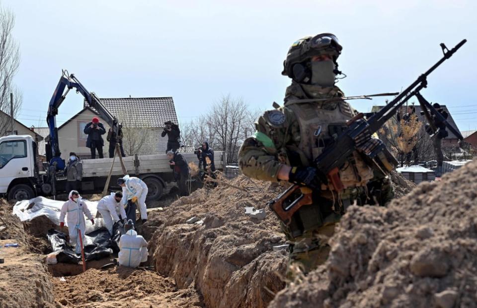 <div class="inline-image__caption"><p>A Ukrainian serviceman looks on as workers exhume bodies from a mass grave in Bucha, north-west of Kyiv. Ukraine says it has discovered 1,222 bodies in Bucha and other towns. </p></div> <div class="inline-image__credit">AFP via Getty Images</div>