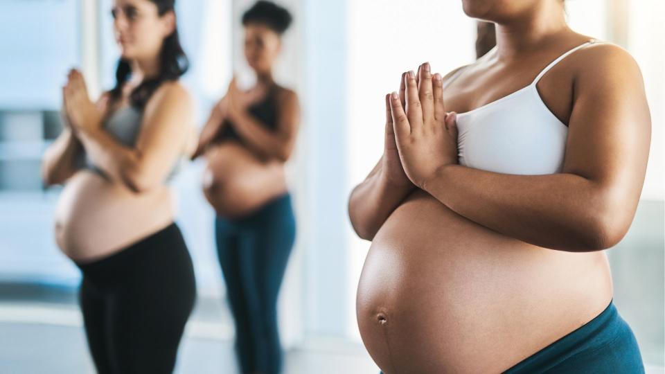 a group of young pregnant women meditating and practising yoga together in studio