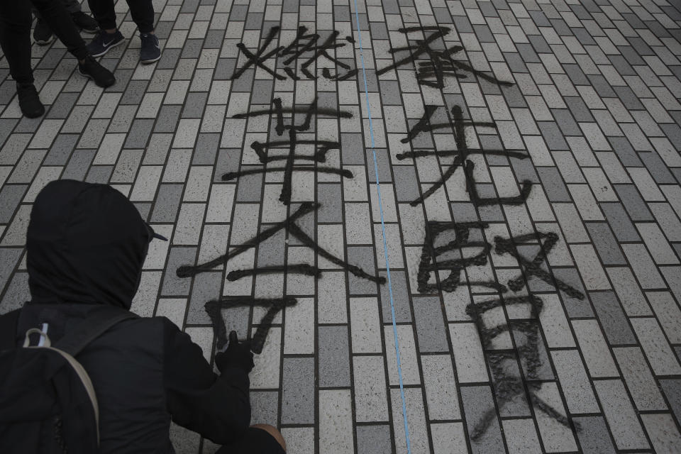 A pro-democracy university student writes in Chinese "To take up the torch of our intellectual forebears and ignite the fire of revolution" at the campus of the University of Hong Kong, Wednesday, Nov. 6, 2019. The protests began in early June against a now-abandoned extradition bill that would have allowed suspects to be sent for trials in mainland China, which many saw as infringing of Hong Kong's judicial freedoms and other rights that were guaranteed when the former British colony returned to China in 1997. The movement has since grown into calls for greater democracy and police accountability. (AP Photo/Kin Cheung)