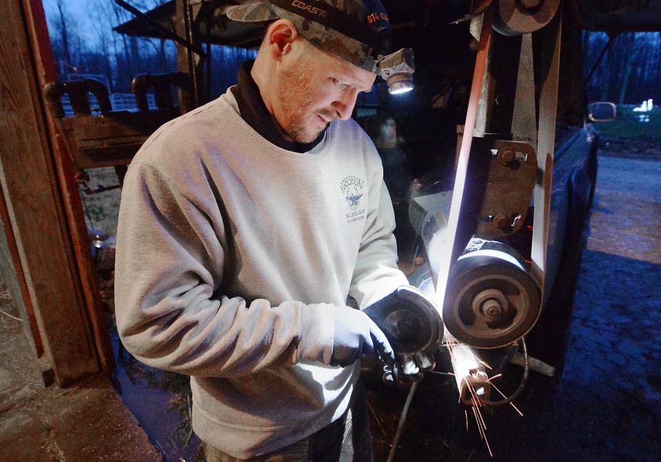 Bill Spellman, 40, grinds and shapes a new horseshoe at the back of his truck while shoeing horses at the home of a customer in North East Township. Spellman designed the truck to have all tools at the ready when working with clients and veterinarians.