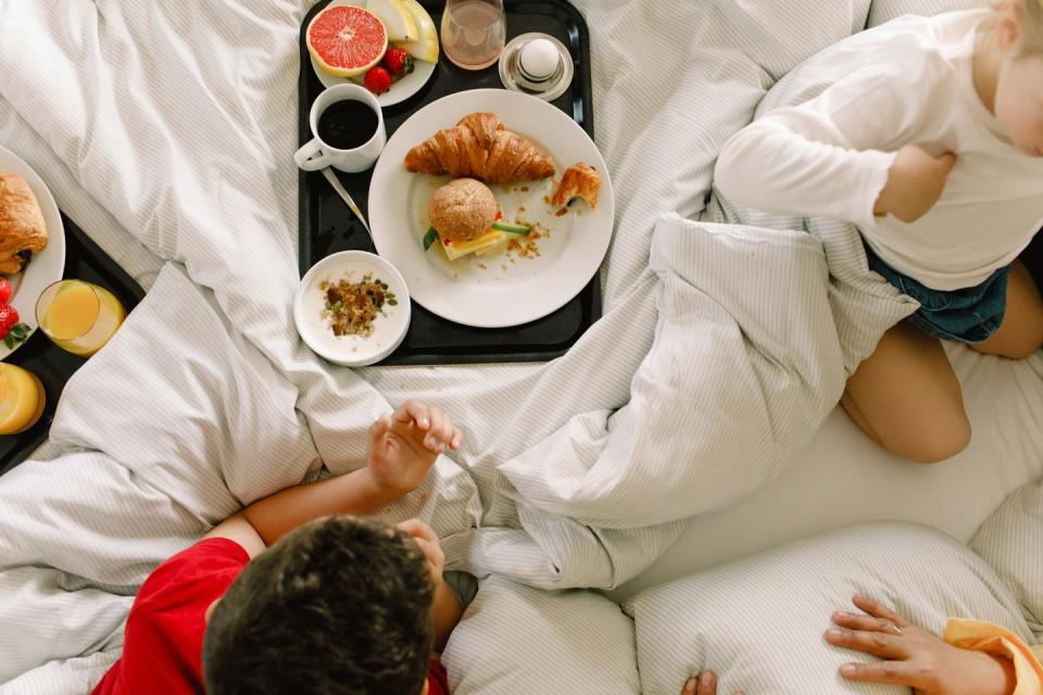 directly above shot of family having breakfast on bed in hotel