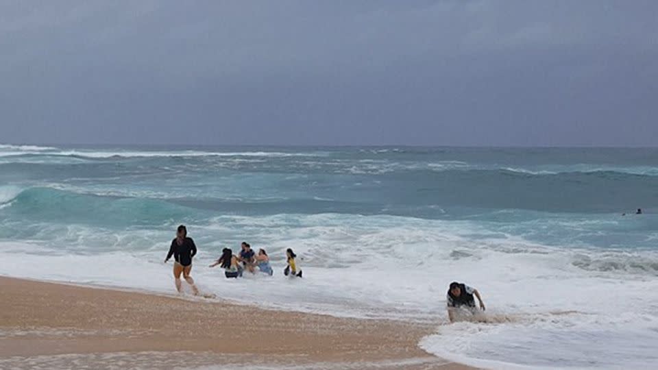 While his rescuers pulled him from the fast moving tide, his grandfather (far right) had issues of his own. Source: Junkin Media