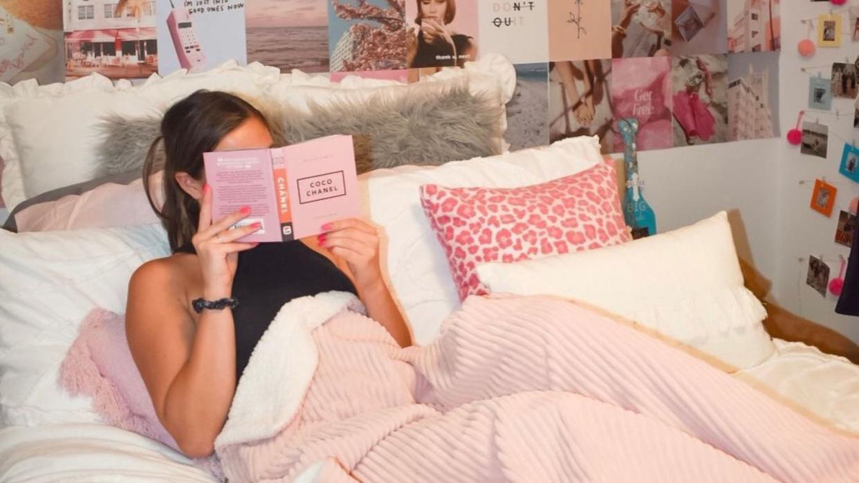  A girl holding a pink book in bed 