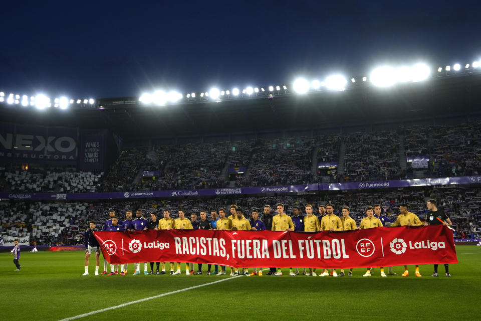 Los jugadores del Barcelona y el Valladolid exhiben una pancarta con la frase "Racistas, fuera del fútbol" previo al partido de la Liga española, el martes 23 de mayo de 2023, en Valladolid. (AP Foto/Manu Fernández)