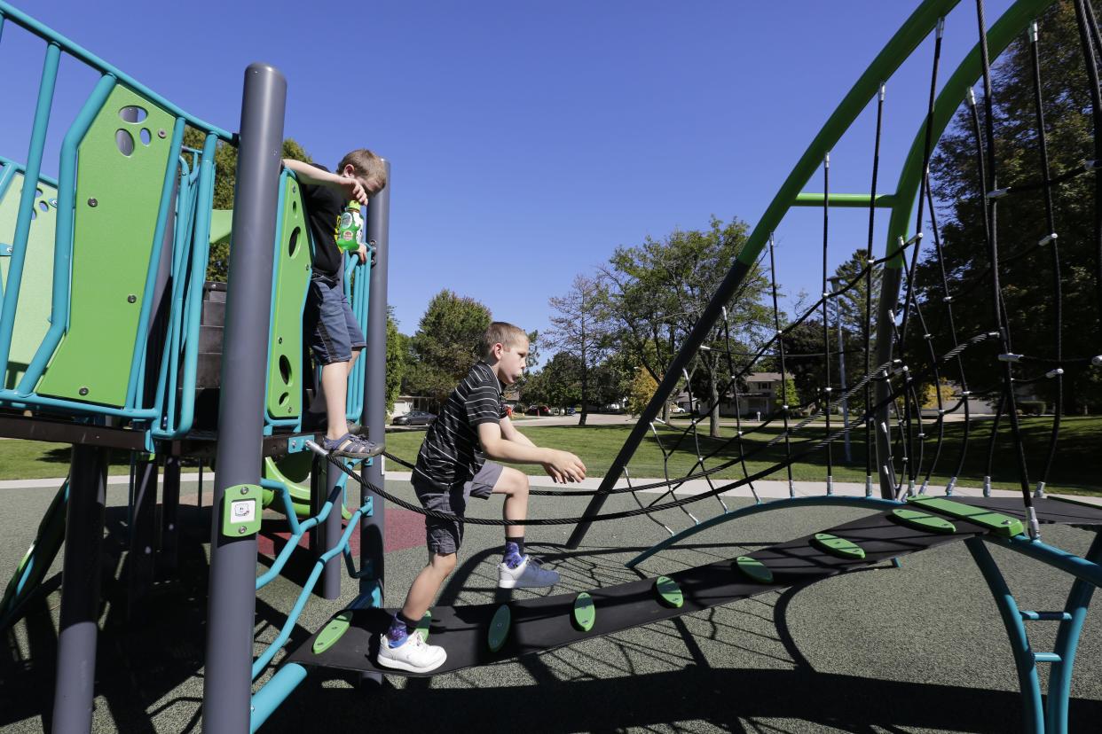 Teddy Blondheim, 10, right, navigates playground equipment with his brother AJ, then 11, in August 2023 at Westhaven Circle Park in Oshkosh.