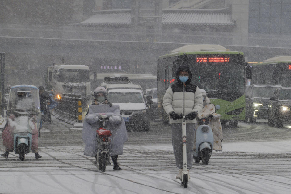 Motorists move through a street during a snowfall in Xi'an in northwest China's Shaanxi province, Wednesday, Feb. 21, 2024. Heavy snow has blanketed northern and central China, disrupting traffic and forcing schools to cancel classes. (Chinatopix Via AP)