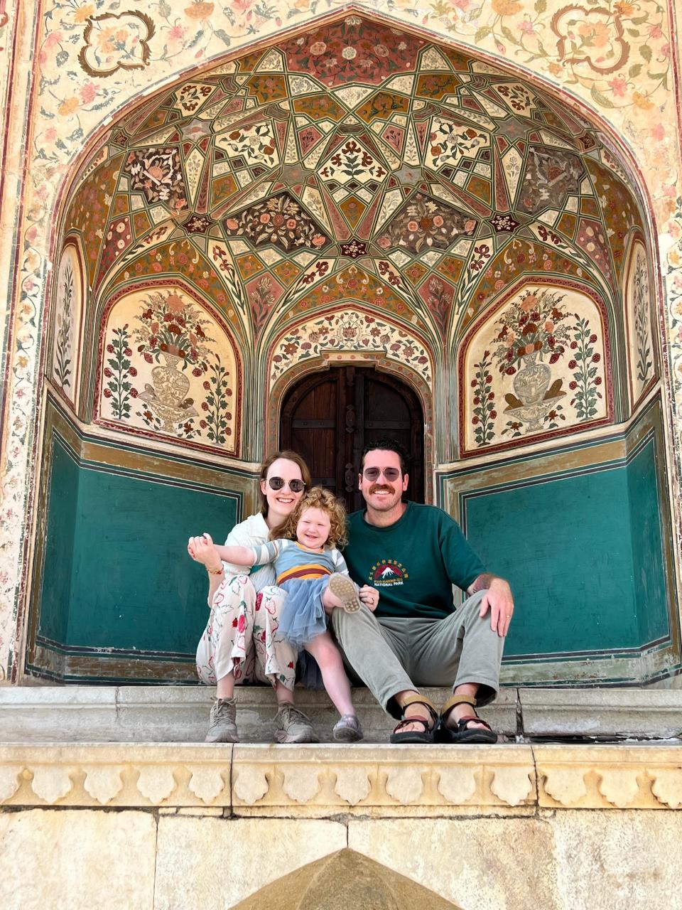 A mother, father, and daughter pose under a tiled dome.