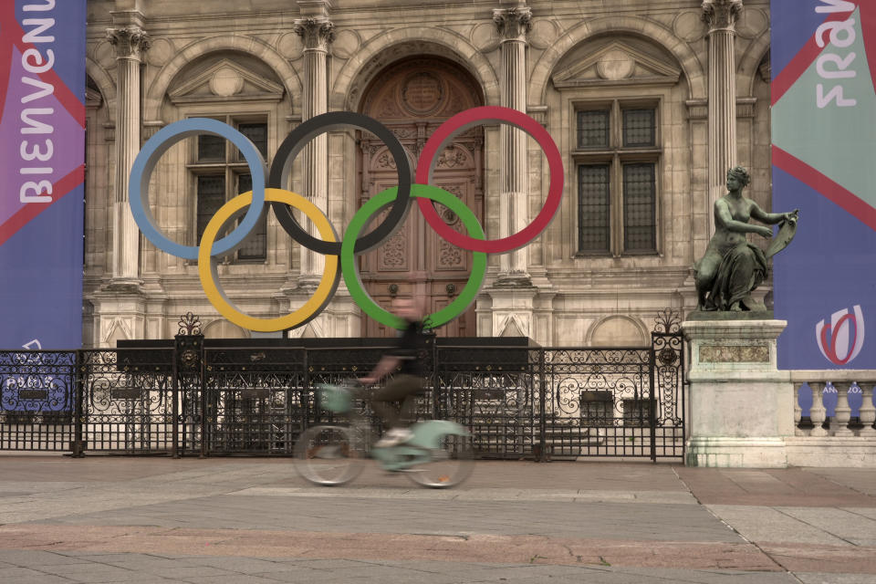A woman rides past the Olympic rings outside the Paris city hall, in Paris, Wednesday, Sept. 13, 2023. Years of efforts to turn car-congested Paris into a more bike-friendly city are paying off ahead of the 2024 Olympics, with increasing numbers of people using the French capital's growing network of cycle lanes. (AP Photo/John Leicester)