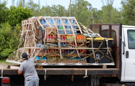 A worker secures relief supplies for Hurricane Dorian victims delivered by a U.S. Coast Guard C-130 crew in Andros