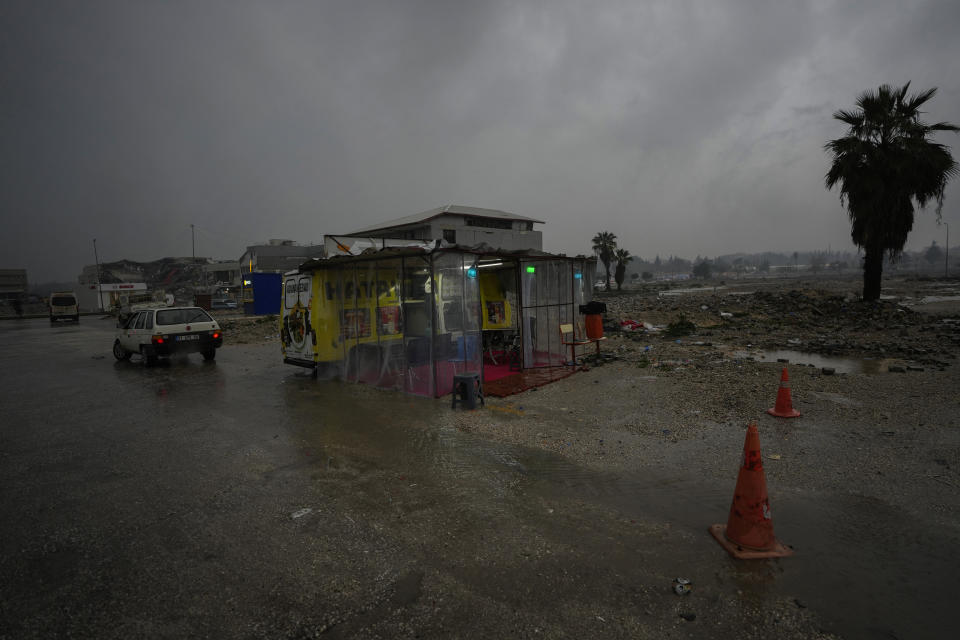 A truck serving fast food is parked amid the remains of buildings destroyed by a powerful earthquake that struck on Feb. 6, 2023, in the city of Antakya, southern Turkey, Friday, Jan. 12, 2024. Many people in the stricken area are struggling to rebuild a year after the devastation. (AP Photo/Khalil Hamra)