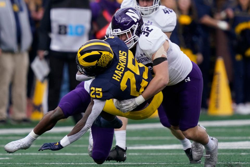 Michigan Wolverines running back Hassan Haskins (25) is tackled by Northwestern Wildcats linebacker Bryce Gallagher (32) during the first half of an NCAA college football game, Saturday, Oct. 23, 2021, in Ann Arbor, Mich. (AP Photo/Carlos Osorio)