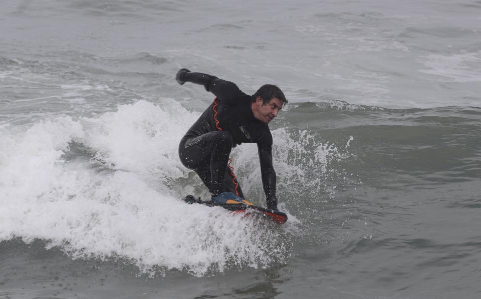 Alessandro Currarino surfs off Waikiki beach in the Miraflores district of Lima, Peru, Thursday, June 11, 2020. The emblematic surfers who dot Peru's coastline are retaking to the waves as the hard-hit nation relaxes COVID-19 related restrictions on outdoor sports. (AP Photo/Martin Mejia)