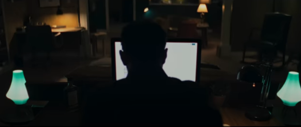 person in dark looking at computer screen