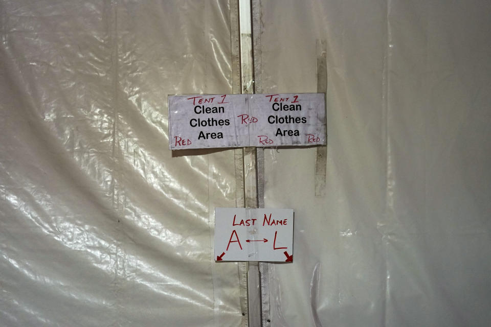 Signs mark a clothes drop in a tent city for electrical workers in Amelia, La., Thursday, Sept. 16, 2021. When Hurricane Ida was brewing in the Gulf of Mexico, the grass was chest high and the warehouse empty at this lot in southeastern Louisiana. Within days, electric officials transformed it into a bustling “tent city” with enormous, air-conditioned tents for workers, a gravel parking lot for bucket trucks and a station to resupply crews restoring power to the region. (AP Photo/Gerald Herbert)