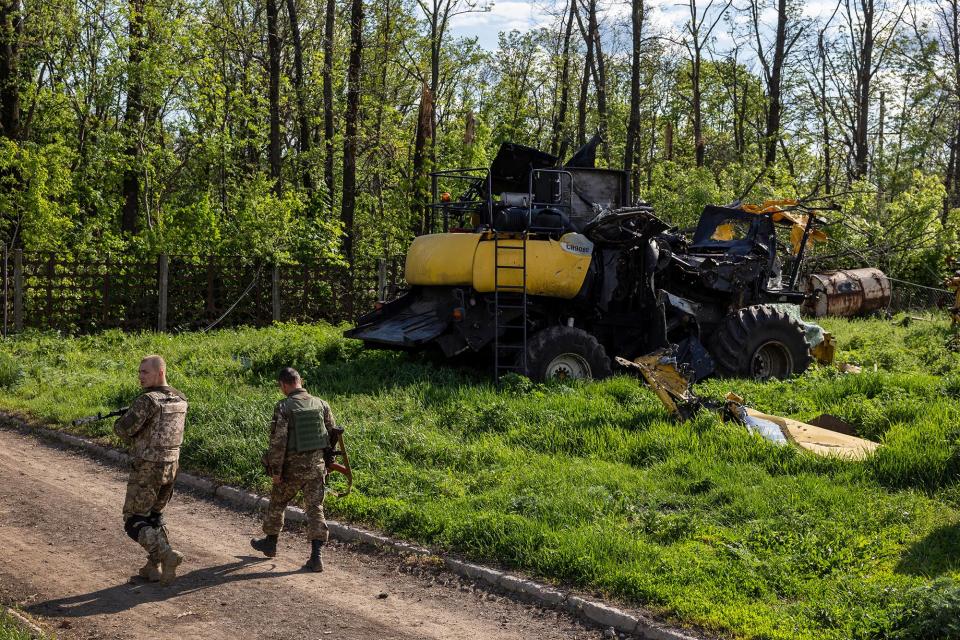 Ukrainian soldiers pass farm equipment destroyed by Russian tanks on May 14, 2022. - Credit: John Moore/Getty Images