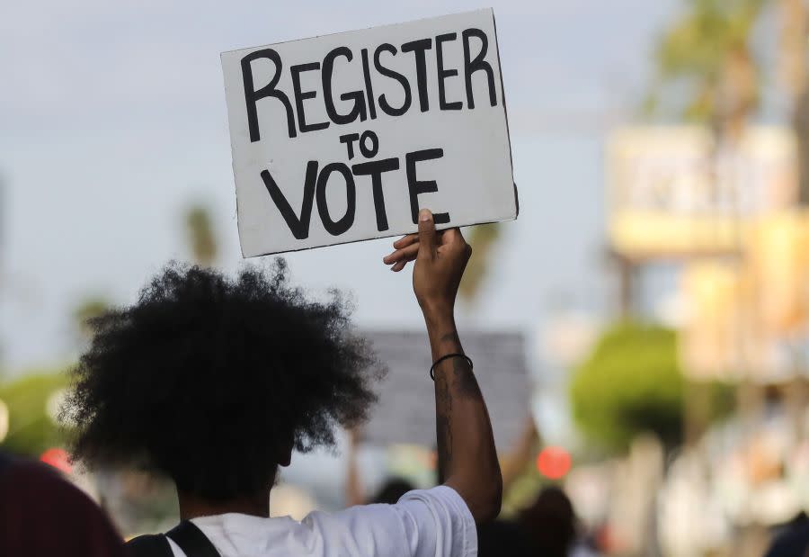 A protester carries a ‘Register to Vote’ sign during a peaceful demonstration against racism and police brutality on June 6, 2020, in Los Angeles. (Photo by Mario Tama/Getty Images)