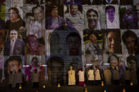 FILE - In this Nov. 1, 2020, file photo, the Archbishop of Lima, Carlos Castillo, center, swings a censer near portraits of COVID-19 victims projected on the facade of Lima's Cathedral during a Mass dedicated to the more than 30,000 deceased in Peru due to COVID 19. Within the framework of Day of the Dead, the Catholic Church decided to project 10,000 photos of victims of COVID-19 on the facade of the Cathedral during a night Mass. (AP Photo/Rodrigo Abd, File)