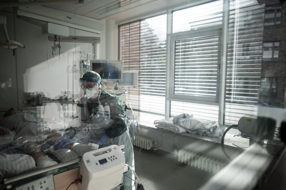 Nursing staff in protective equipment cares for a corona patient in a hospital in Essen, Germany, Wednesday, Oct. 28, 2020. People with a new coronavirus infection are treated in the intensive care unit IT2 in the Operative Centre II of the University Hospital Essen. (Fabian Strauch/dpa via AP)