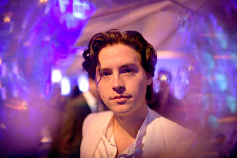 Sprouse stares into the camera while being surrounded by shimmery effects