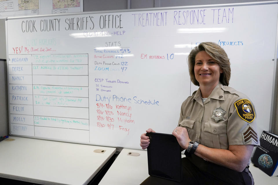 In this Friday, Aug. 13, 2021, photo Sheriff's Police Sgt. Bonnie Busching holds a tablet at the Cook County Sheriff's Office in Chicago. The Cook County Sheriff's Office has started putting people having a crisis face to face with mental health professionals before they lash out at deputies or try to harm themselves and to do it they're taking a page out of countless businesses forced hold their meeting virtually. (AP Photo/Nam Y. Huh)