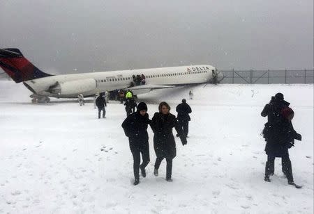 Passengers walk from a Delta jet which skidded off the runway at LaGuardia airport in a photo provided by New York Giants NFL tight end Larry Donnell in New York City March 5, 2015. REUTERS/Larry Donnell