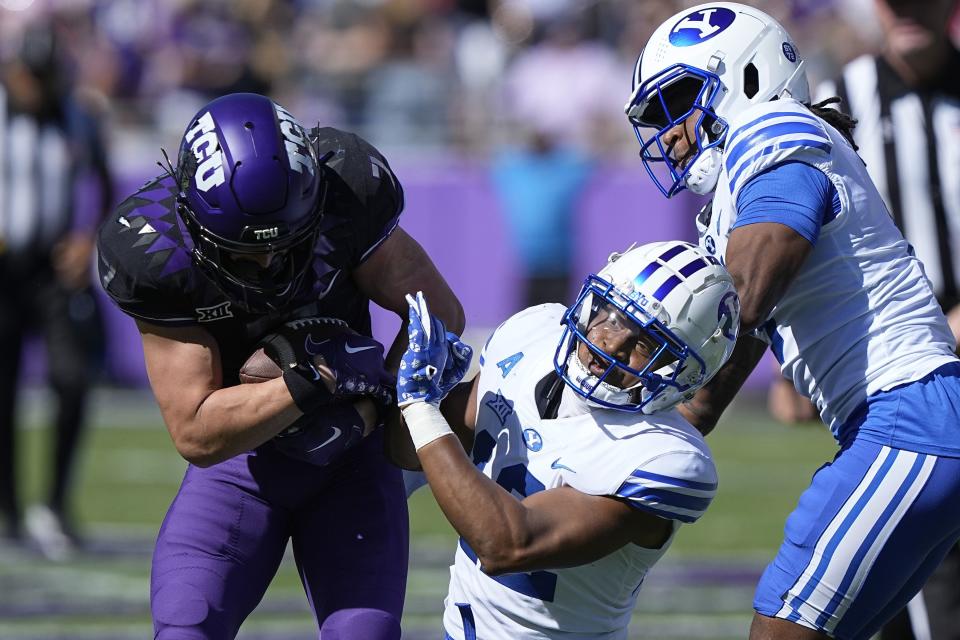 On the way to scoring a touchdown, TCU wide receiver JP Richardson, left, breaks a tackle against BYU safety Malik Moore, center, and cornerback Eddie Heckard, right, during the first half of an NCAA college football game Saturday, Oct. 14, 2023, in Fort Worth, Texas. | LM Otero, Associated Press