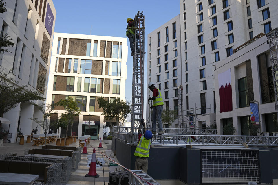 Migrant workers install a stage in Msheireb Downtown ahead of the Asian Cup soccer tournament in Doha, Qatar, Wednesday, Jan. 10, 2024. The plight of migrant workers in Qatar came under the spotlight for more than decade after the gas-rich Middle Eastern emirate was awarded the World Cup in 2010. Workers labored in the searing heat to build over $200 billion worth of stadiums and infrastructure that helped make the tournament such a success. (AP Photo/Aijaz Rahi)