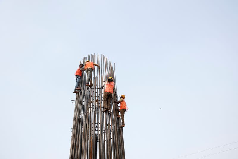 Construction workers work to build a pillar at a construction site during a hot summer day in New Delhi