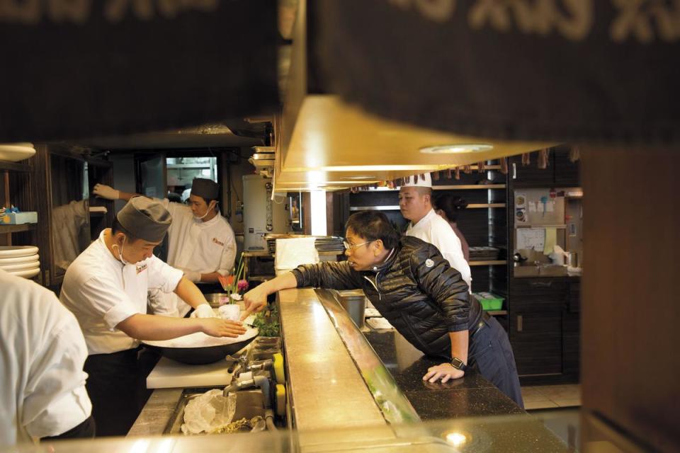 黃文童（右前）在餐廳打造專屬的日本料理吧台，對食材、擺盤以及師傅料理手法要求嚴格，也會親自指導。
