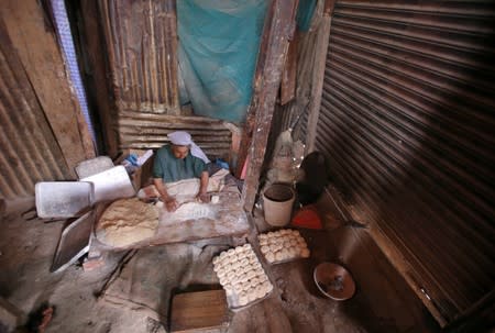 Baker prepares dough inside a bakery workshop with a closed shutter, after restrictions were eased following the scrapping of the special constitutional status for Kashmir by the Indian government, in Srinagar