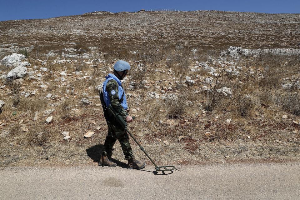 Irish UN peacekeepers use mine detectors as they patrol near the fields struck by Israeli army shells in the southern Lebanese-Israeli border village of Maroun el-Ras, Lebanon, Monday, Sept. 2, 2019. The Lebanon-Israel border was mostly calm with U.N. peacekeepers patrolling the border Monday, a day after the Lebanese militant Hezbollah group fired a barrage of anti-tank missiles into Israel, triggering Israeli artillery fire that lasted less than two hours and caused some fires. (AP Photo/Hussein Malla)