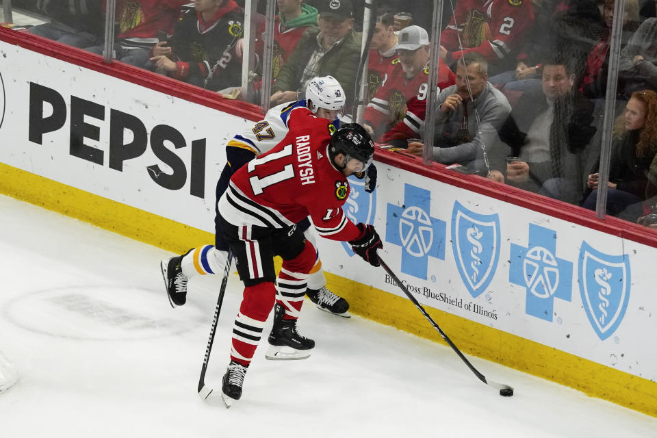 St. Louis Blues defenseman Torey Krug (47) and Chicago Blackhawks right wing Taylor Raddysh (11) battle for the puck during the second period of an NHL hockey game Saturday, Dec. 9, 2023, in Chicago. (AP Photo/David Banks)