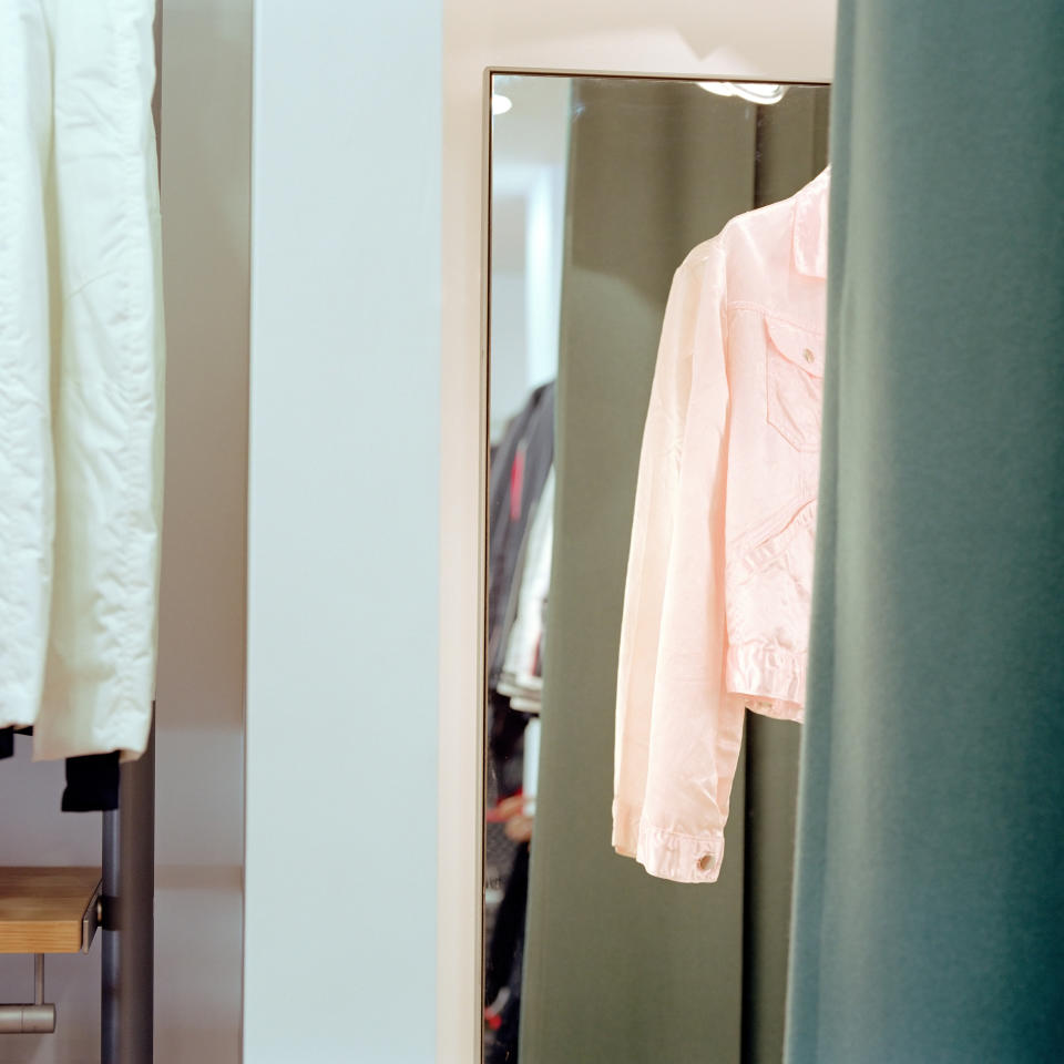 clothing hanging in a fitting room in front of a mirror