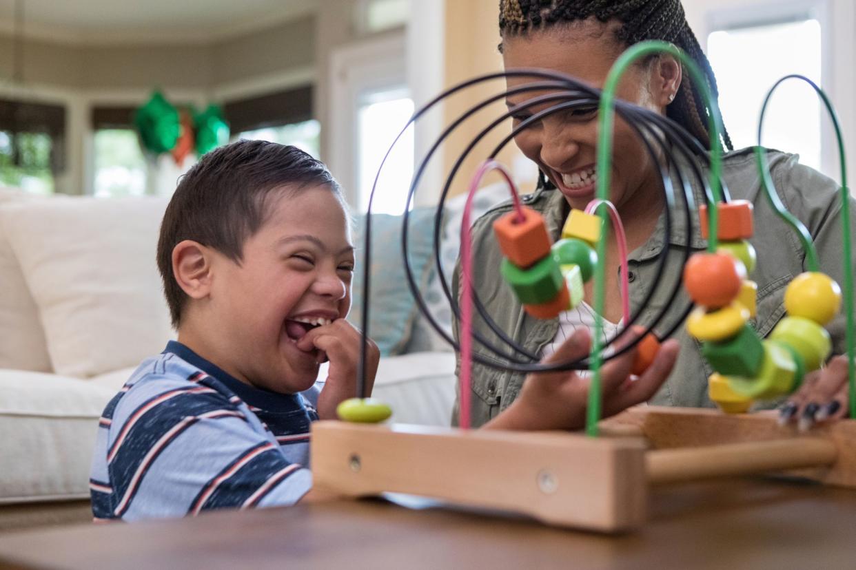 When the mid adult mom and her special needs son play in the living room, they laugh together.