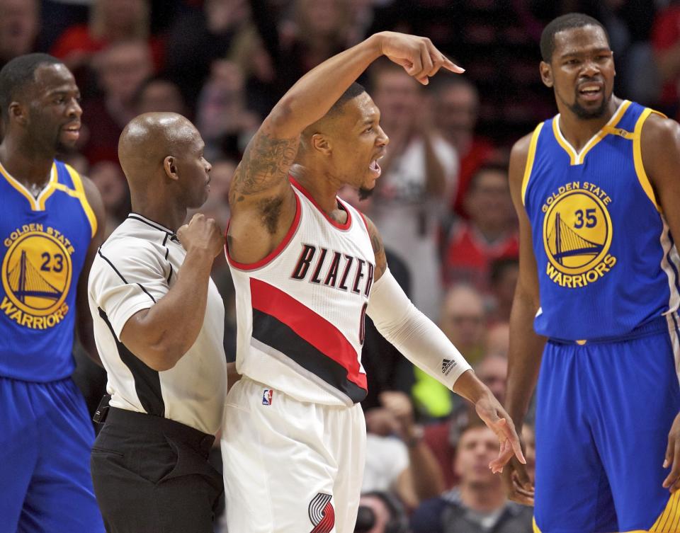 Damian Lillard (center) isn't sure Draymond Green (left) and Kevin Durant (right) can protect the paint against him. (AP)