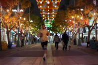 A jogger runs through a shopping district Thursday, Nov. 19, 2020, in Santa Monica, Calif. California Gov. Gavin Newsom is imposing an overnight curfew as the most populous state tries to head off a surge in coronavirus cases. On Thursday, Newsom announced a limited stay-at-home order in 41 counties that account for nearly the entire state population of just under 40 million people. (AP Photo/Marcio Jose Sanchez)