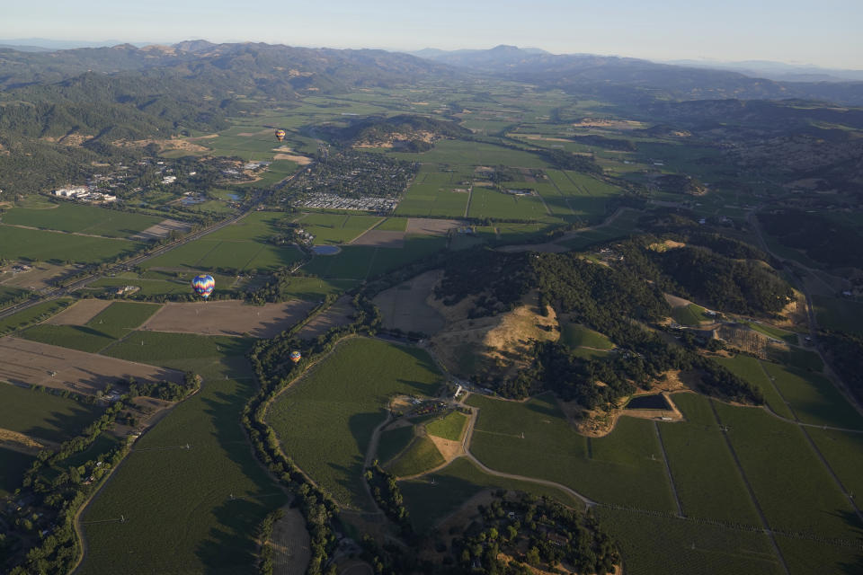 Wappo Hill, at right, and Mt. St. Helena in the background are seen from a Napa Valley Aloft balloon near Yountville, Calif., Monday, June 19, 2023. This year, wine grapes are thriving after a winter of record amounts of rain fell in California, but a recent trip high above the valley in a hot air balloon revealed miles of lush, green vineyards — the only blemish coming from shadows cast by the balloons themselves. (AP Photo/Eric Risberg)