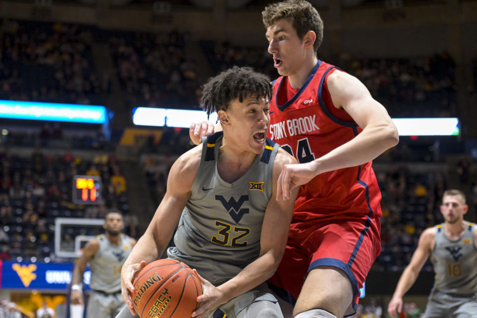 West Virginia forward James Okonkwo (32) protects the ball from Stony Brook center Rocco Muratori (34) during the second half of an NCAA college basketball game Thursday, Dec. 22, 2022, in Morgantown, W.Va. (William Wotring/The Dominion-Post via AP)