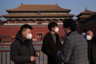 People wearing protective masks stand outside the main entrance of the Forbidden City where a notice is seen saying that the place is closed to visitors for the safety concern following the outbreak of a new coronavirus, in Beijing